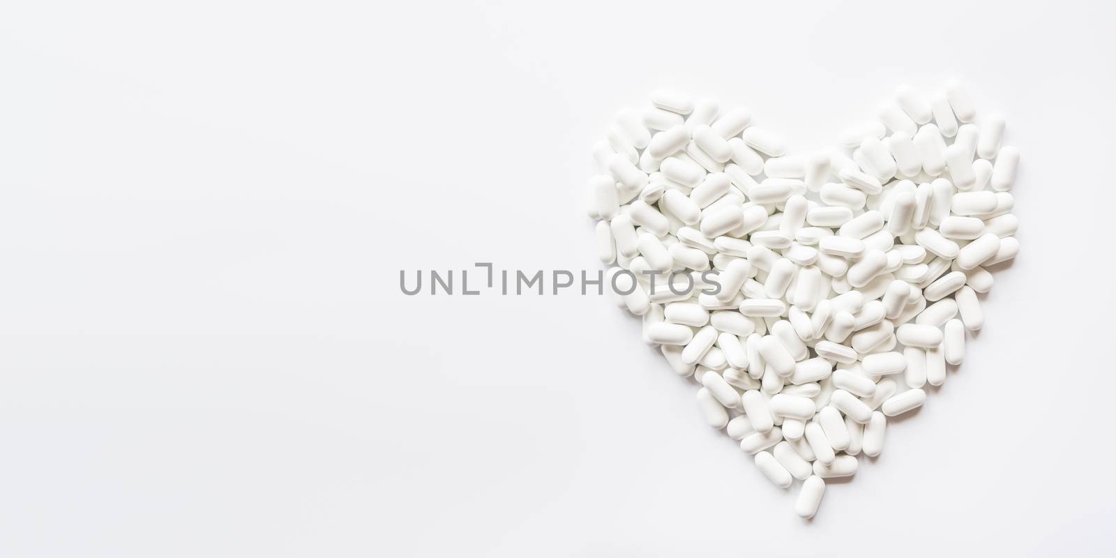 Heart made of white pills. Top view on drugs in shape of heart. Flat lay background with copy space. by aksenovko