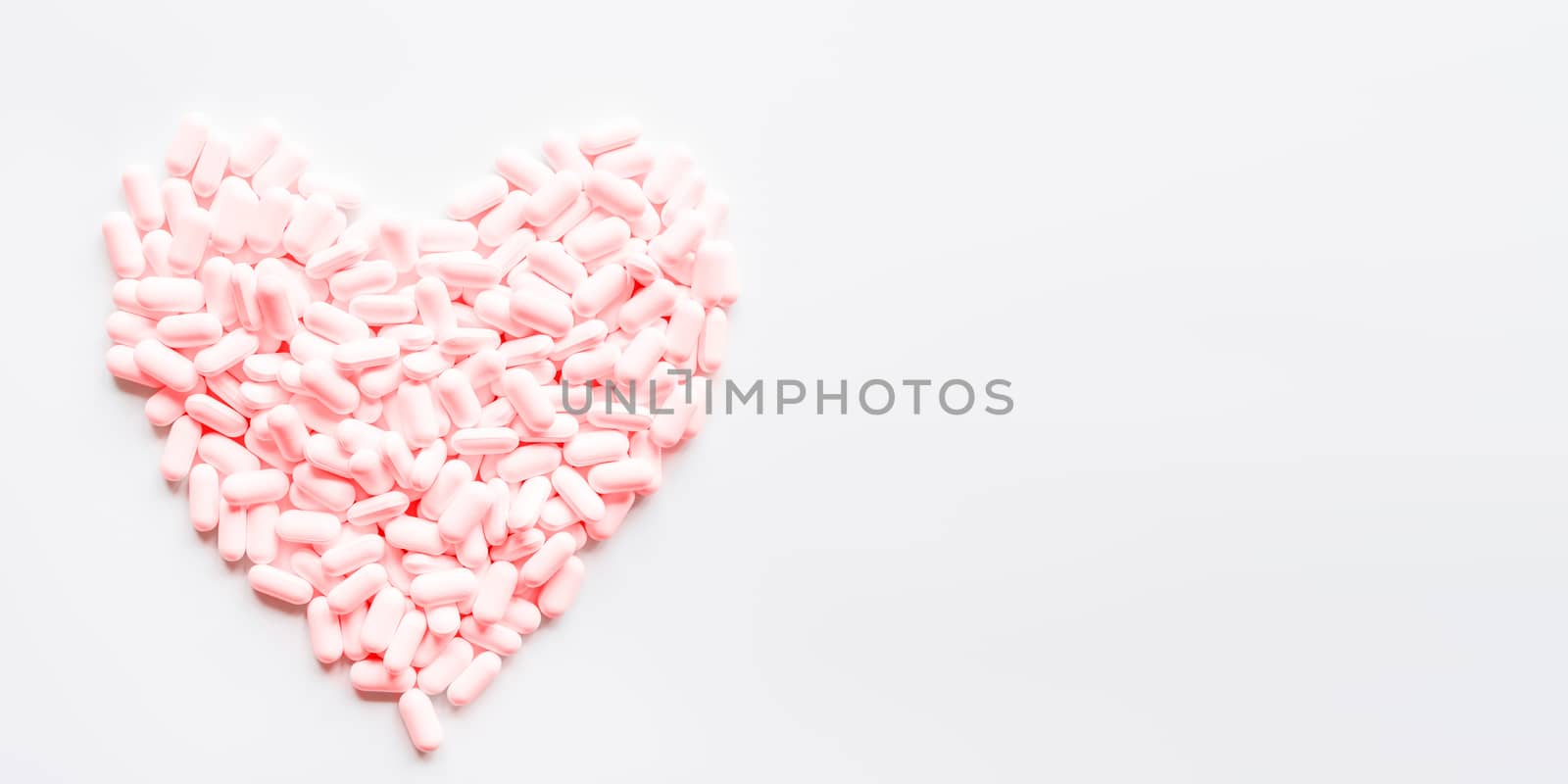 Heart made of pink pills. Top view on drugs in shape of heart. Flat lay white background with copy space.