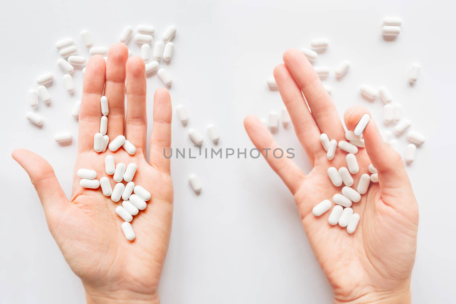 Palm hands full of white scattering pills. Capsules with medicines on light background. Flat lay, top view.