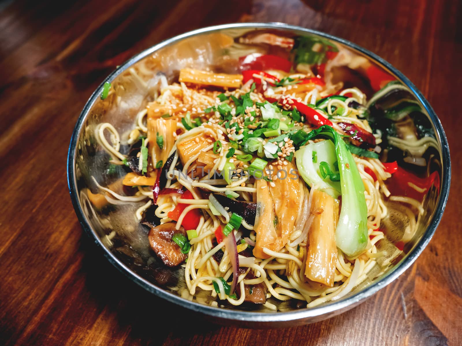 Asian cuisine - noodle with stir fried vegetables. Bowl with food on wooden table.