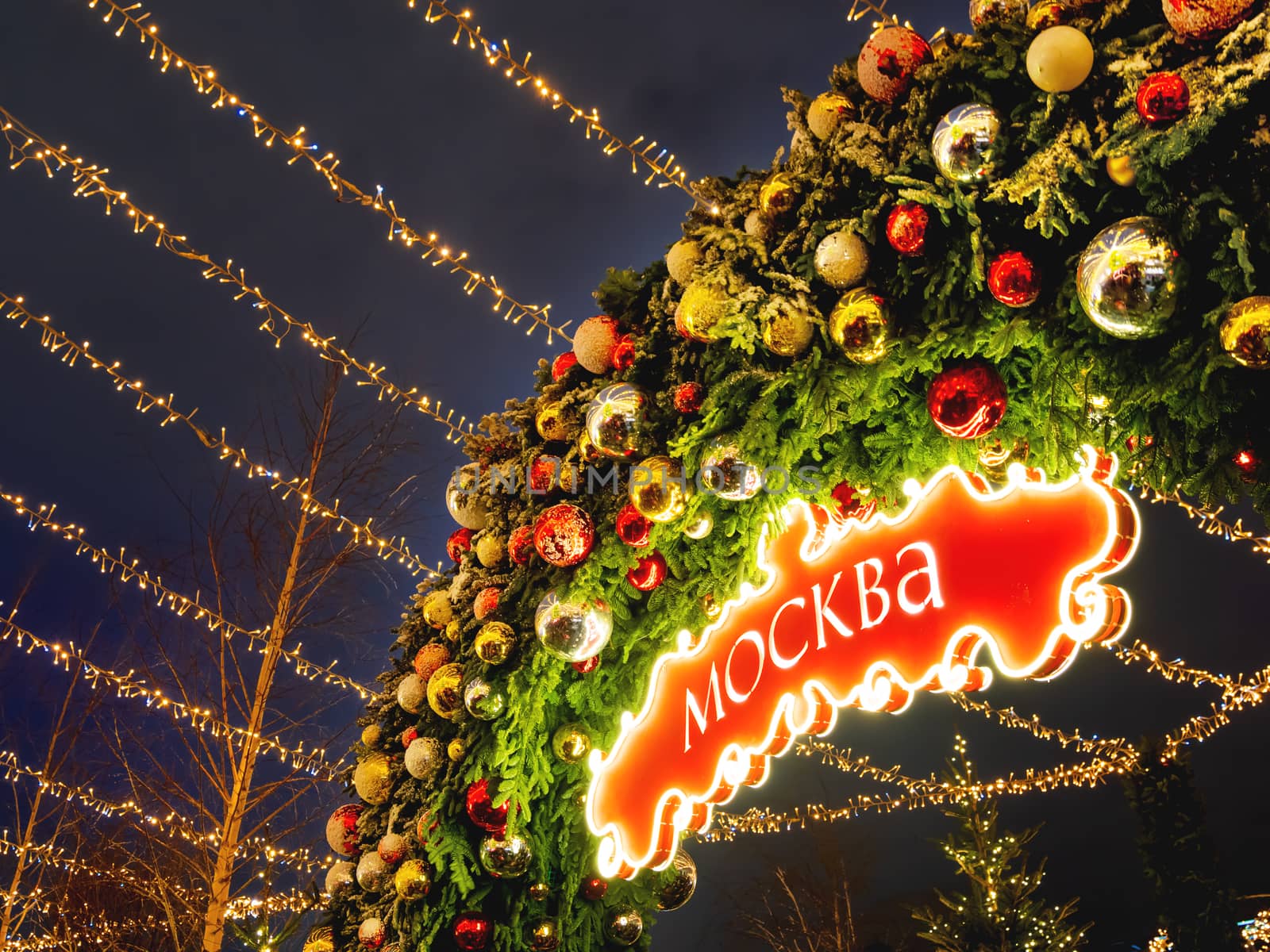 Decorative arch made of fir tree branches with colorful balls and sign with MOSCOW word on it. Outdoor Christmas decorations for New Year celebration. Moscow, Russia.