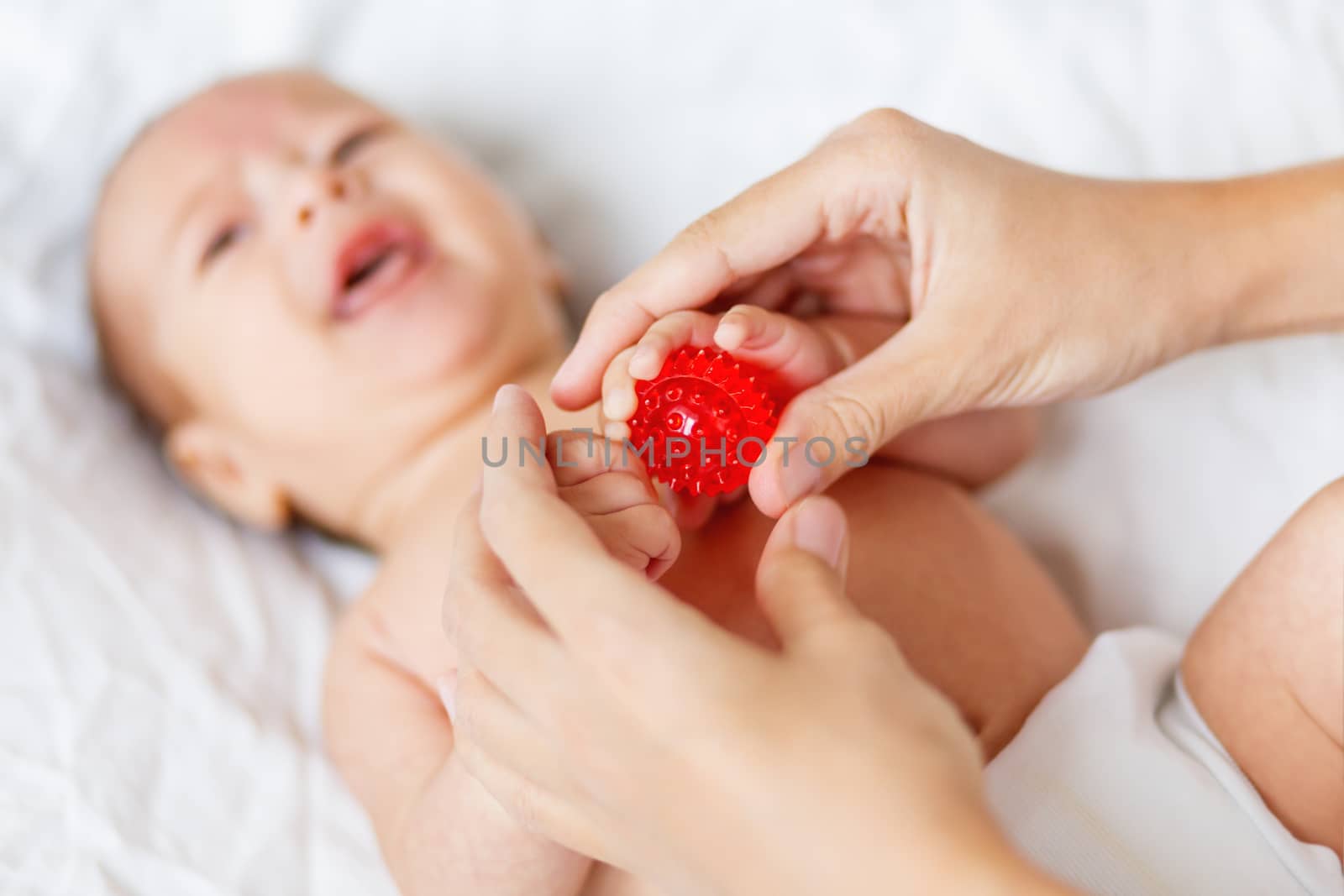 Mother holds newborn baby's palm hands. Tiny fingers in woman's hand. Cozy morning at home.