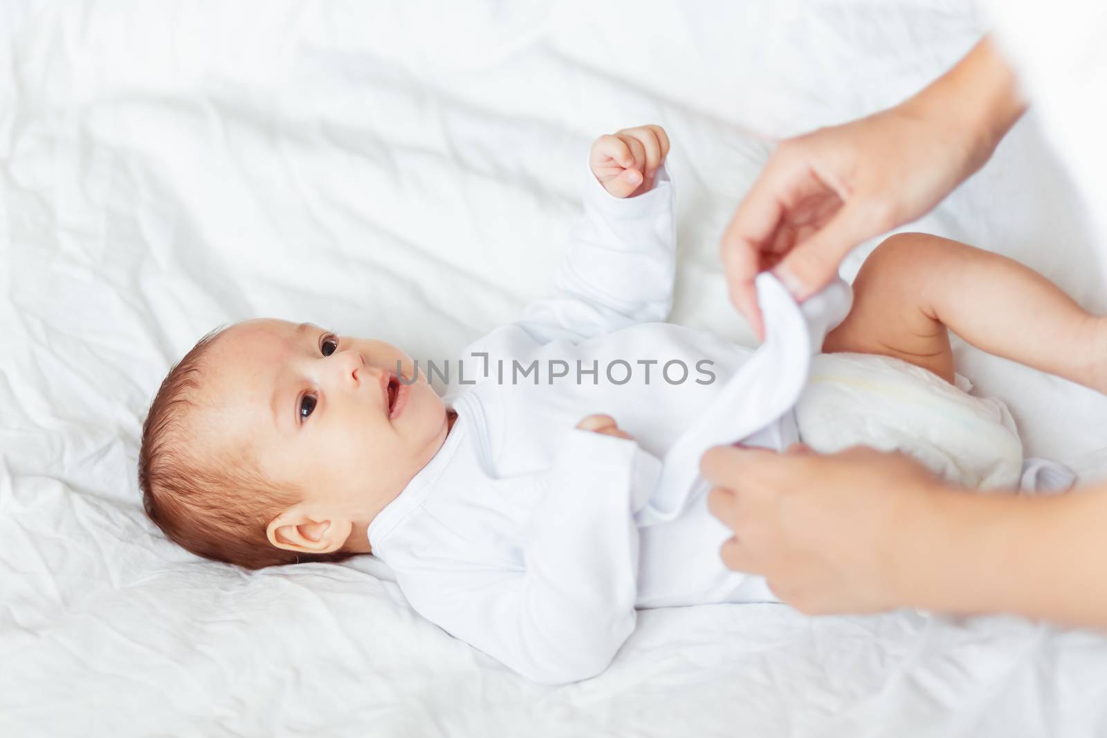 Mother changes the child's clothes. Woman changes a bodysuit for a young son or daughter.