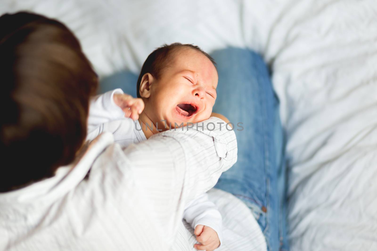 Woman holding a crying child. Mother comforts her little son or daughter.