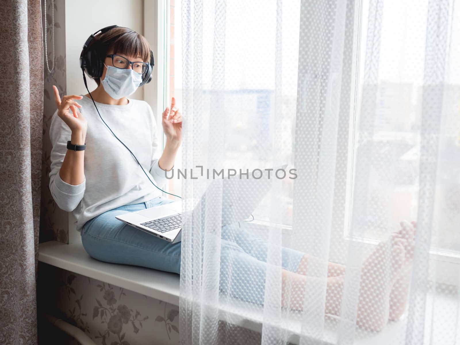 Woman in medical mask remote works from home. She speaks online by aksenovko