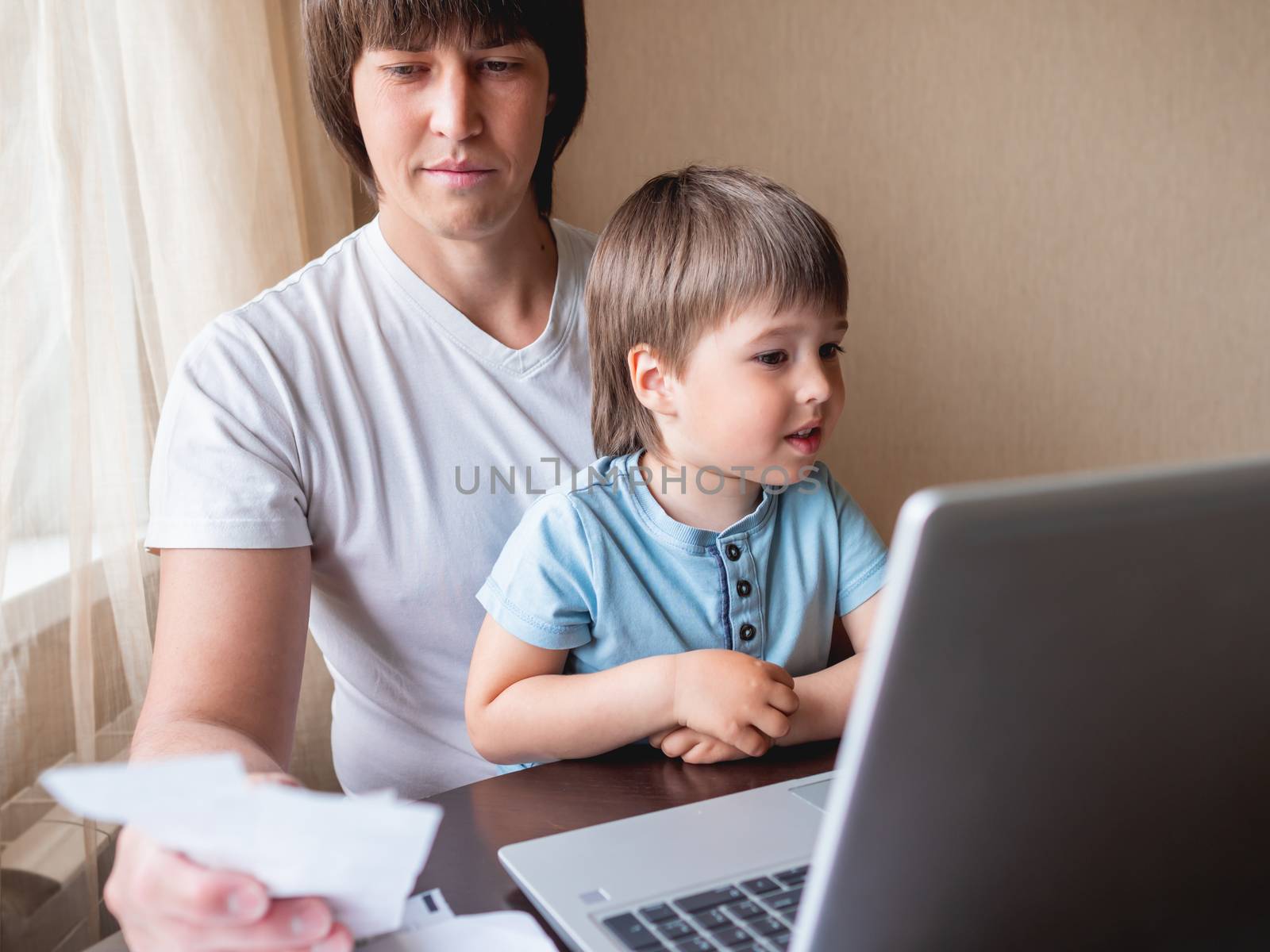 Self-isolation because of coronavirus outbreak. Man is remote working with his little son on self quarantine. Lockdown indoors.