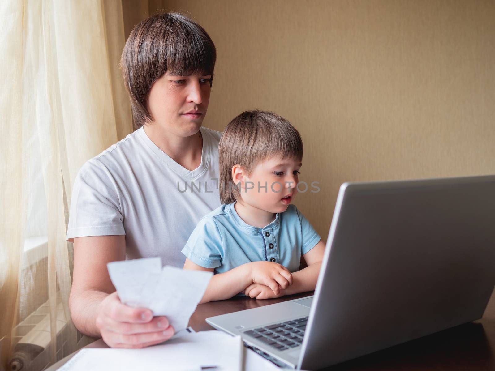 Self-isolation because of coronavirus outbreak. Man is remote working with his little son on self quarantine. Lockdown indoors.