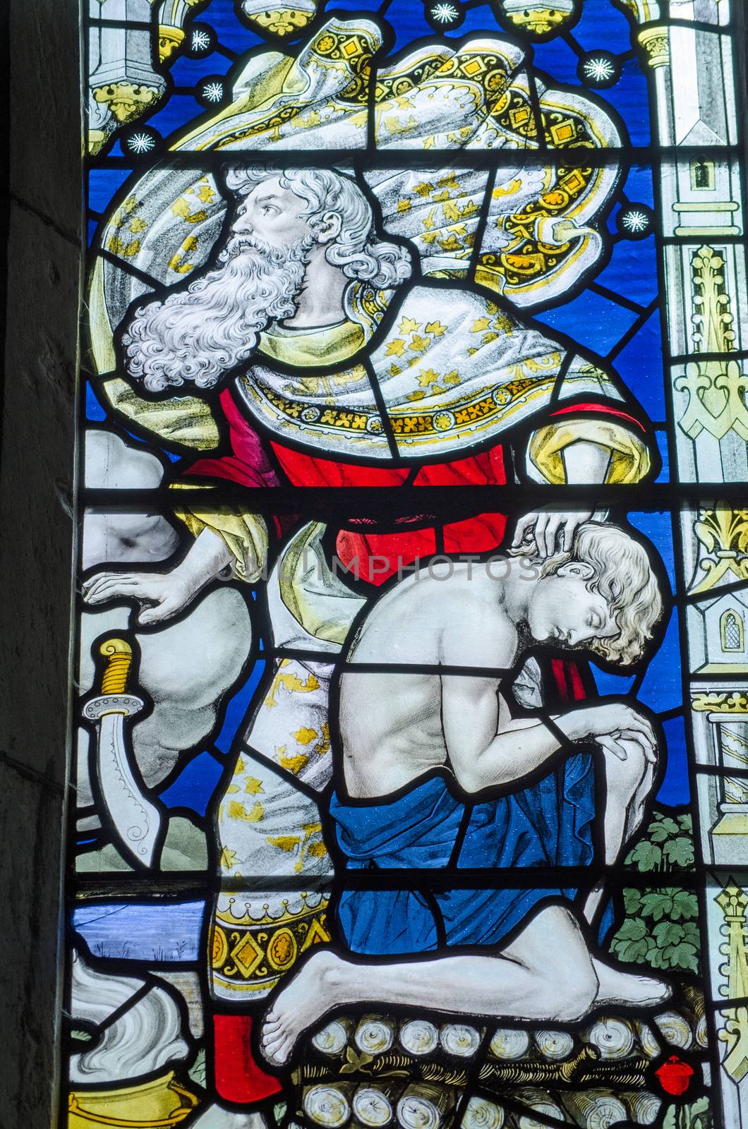 Victorian stained glass window showing Abraham dropping a knife on the command of an angel just as he was about to sacrifice his son Isaac to please God.  Old Testament depicted in an historic window over 100 years old viewed from public place.