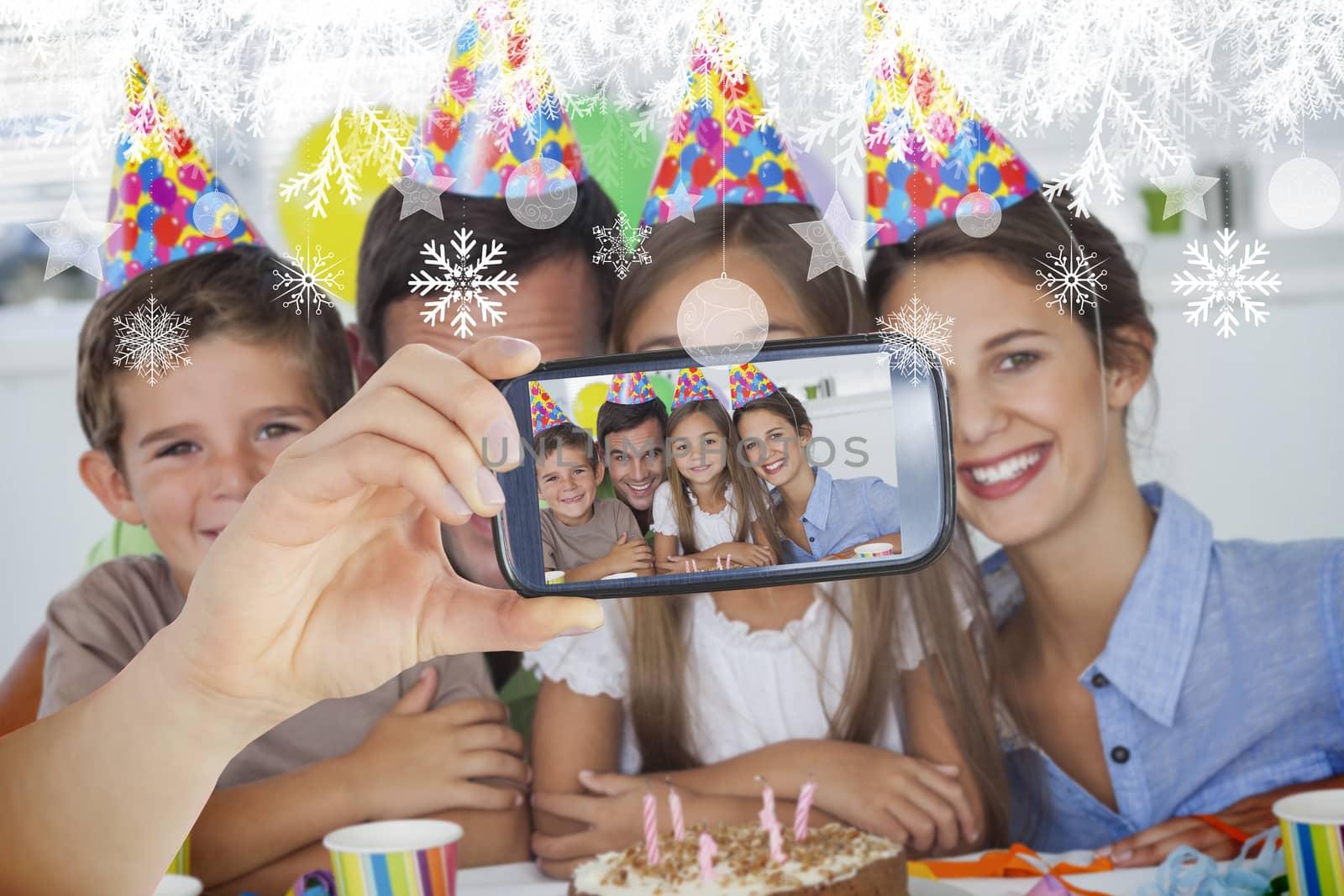 Hand holding smartphone showing photo against hanging decorations