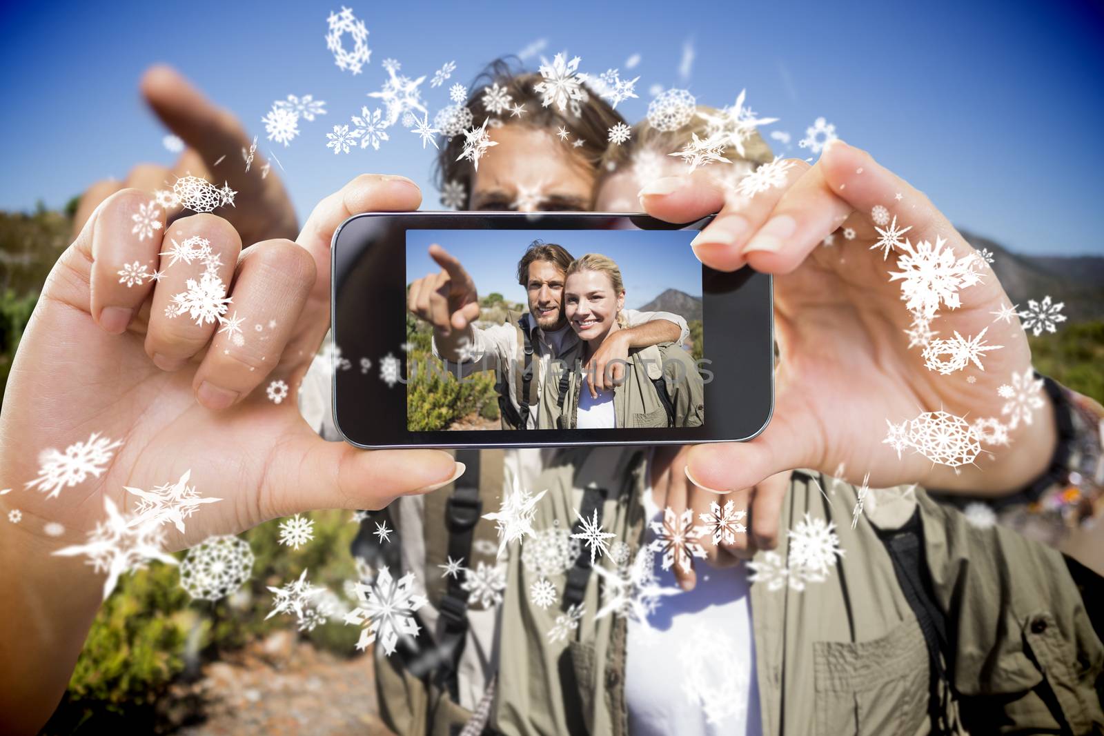 Hand holding smartphone showing photo against snow