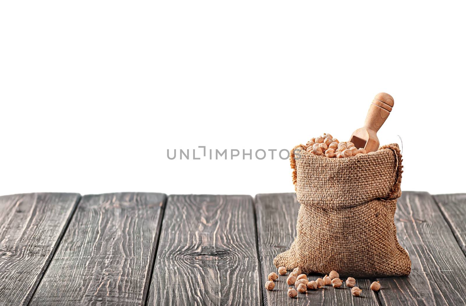 Bag with chickpeas and scoop on table isolated on white background