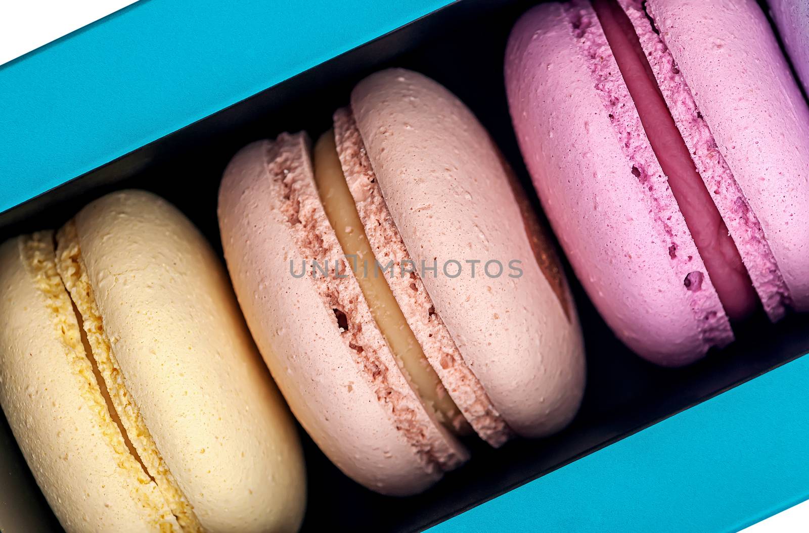 Three macaroons in box closeup on white background