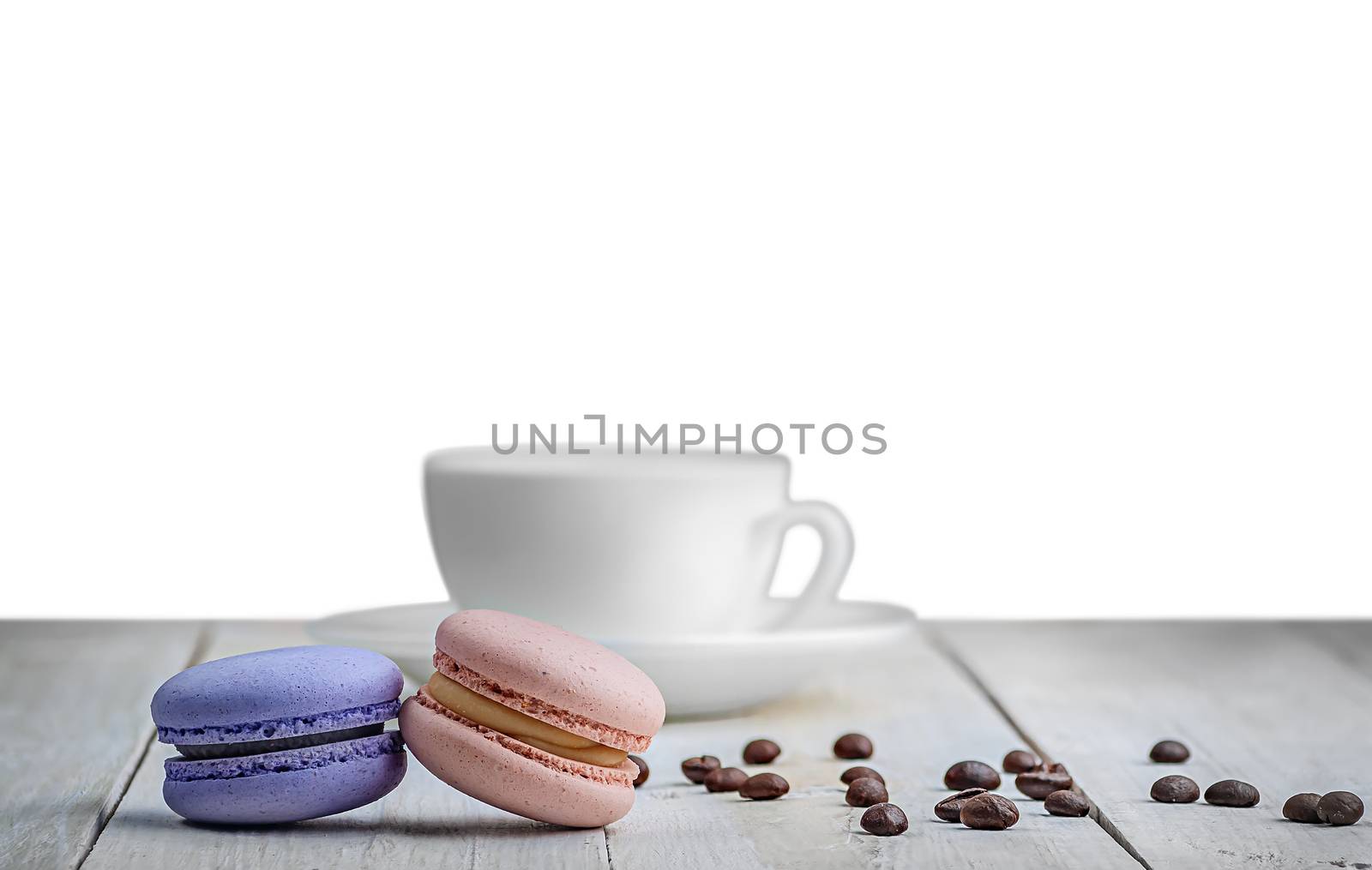 Two macaroons white table with a cup and coffee grains isolated white background