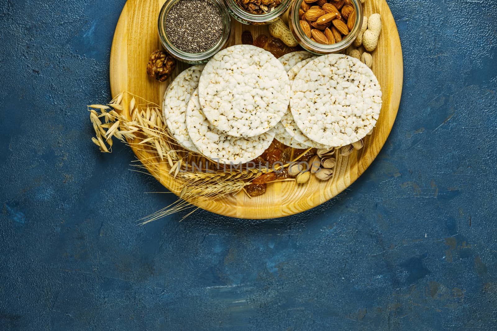Color of 2020 year. Classic Blue, food trendy background. American puffed rice cakes. Healthy snacks with ears of wheat on classic blue concrete surface.