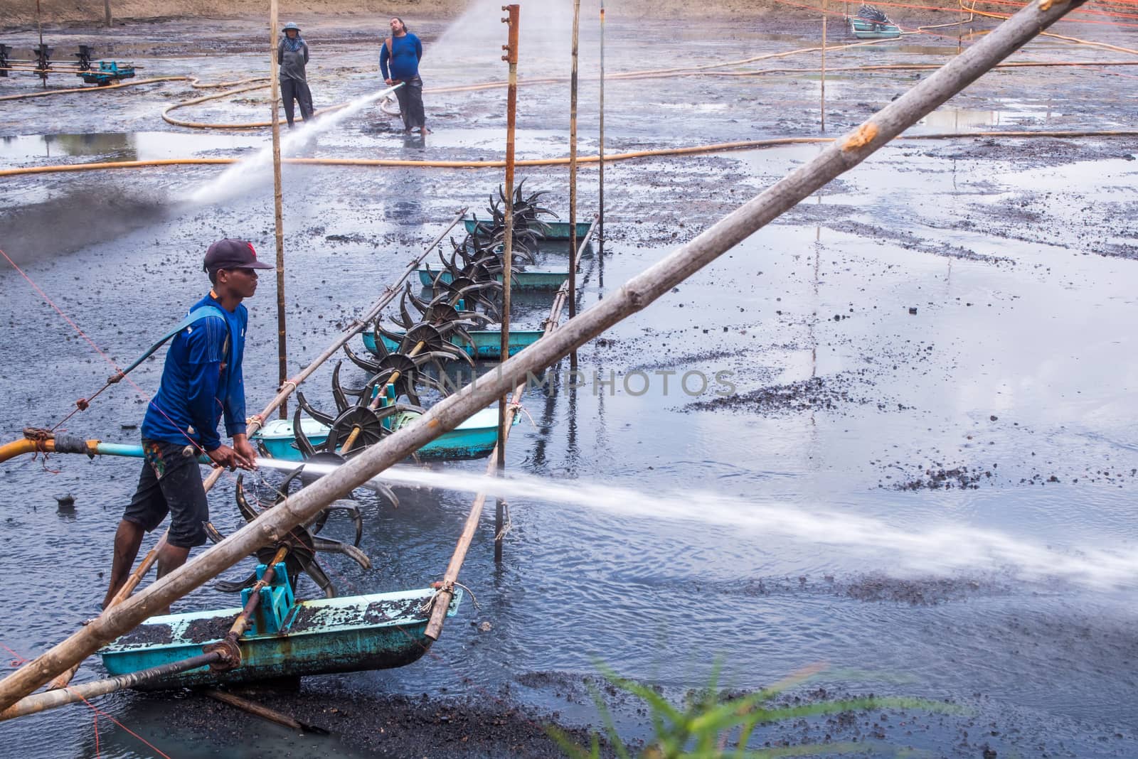 CHACHOENGSAO THAILAND - JULY 13 : Unidentified men control high pressure water jet nozzle to clean the mud at the bottom of the pond on July 13, 2016 to prepare the pond clean, for next time shrimp farming, Chachoengsao, Thailand.