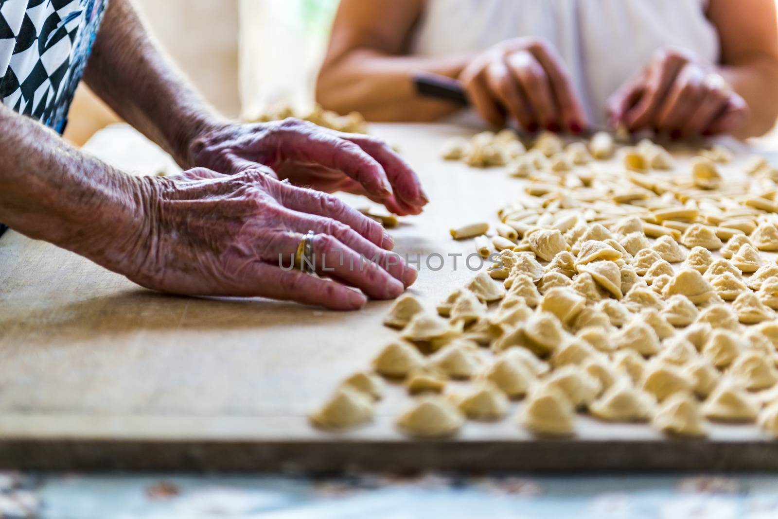 An old woman, while prepare by hands Orecchiette, typical italian pasta.