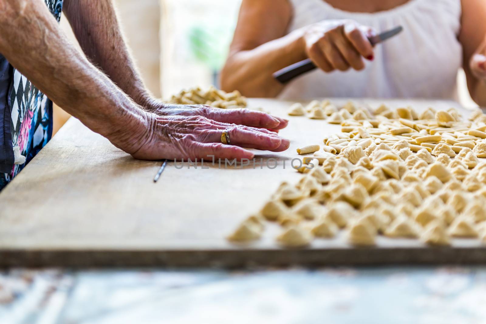 An old woman, while prepare by hands Orecchiette, typical italian pasta.
