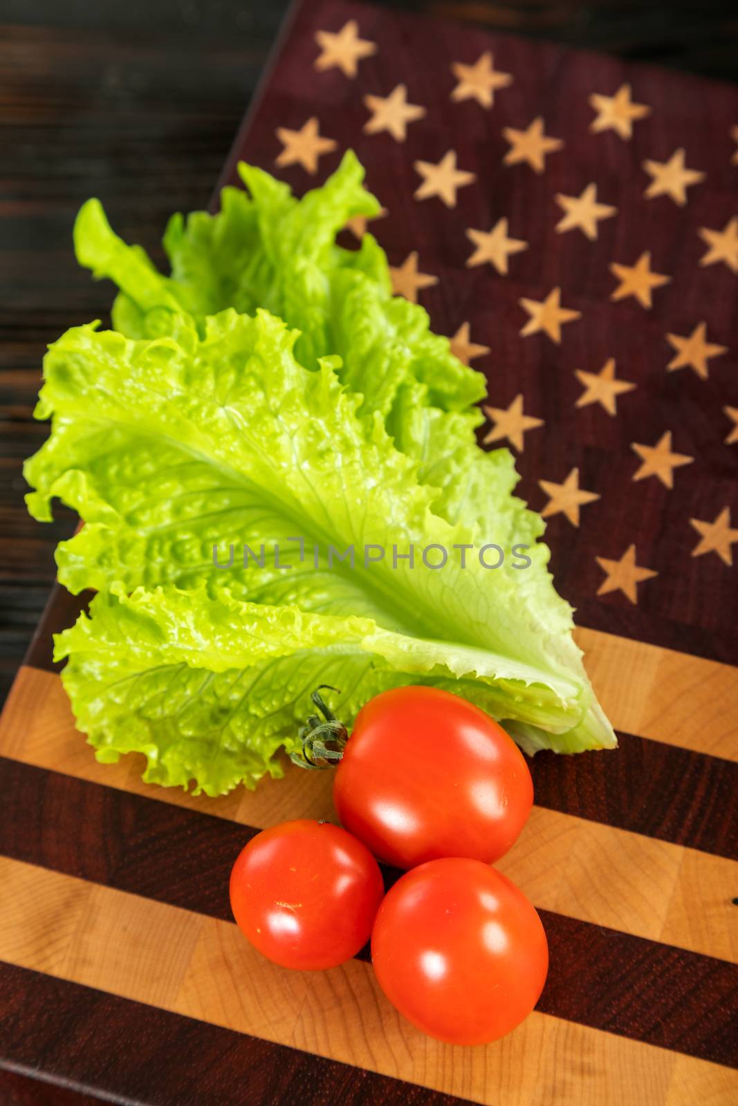 Greens salad and tomatoes on a wooden cutting board