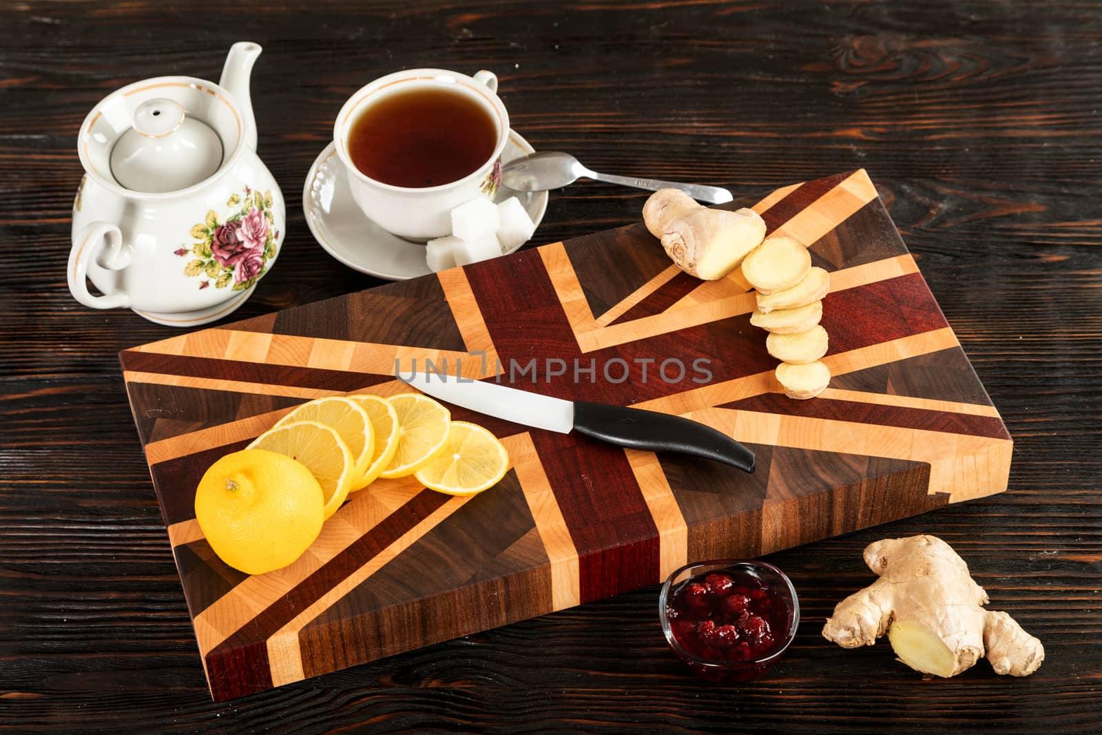 Cup of tea, sliced lemon and a bun on a wooden cutting board