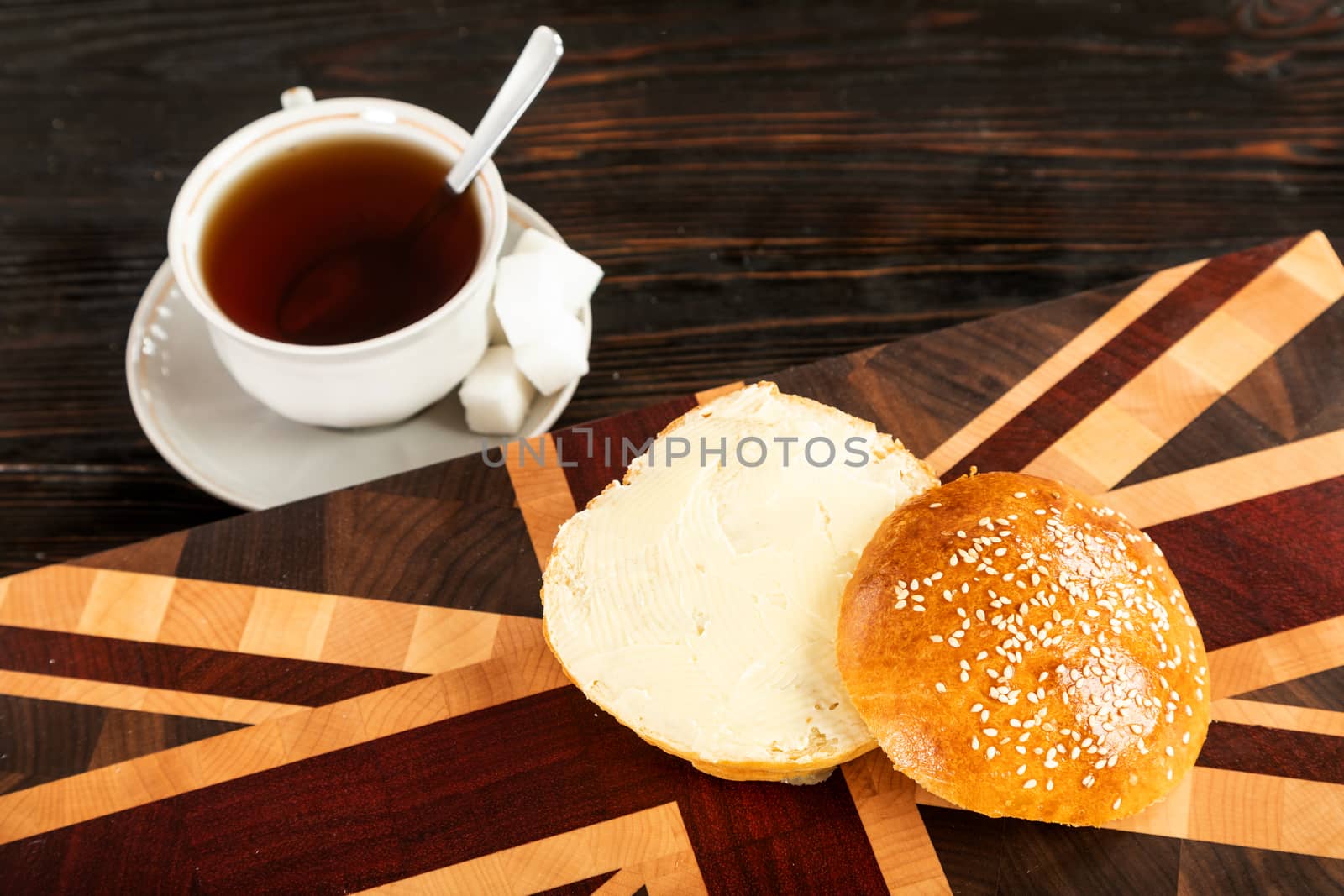 Cup of tea and a bun on a wooden cutting board