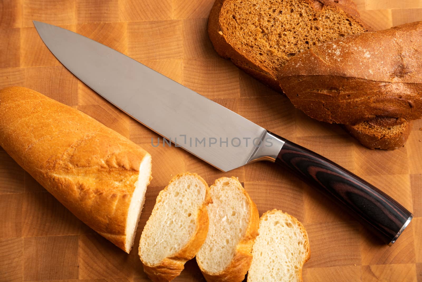 A loaf of bread sliced into slices with a knife on a wooden cutting board