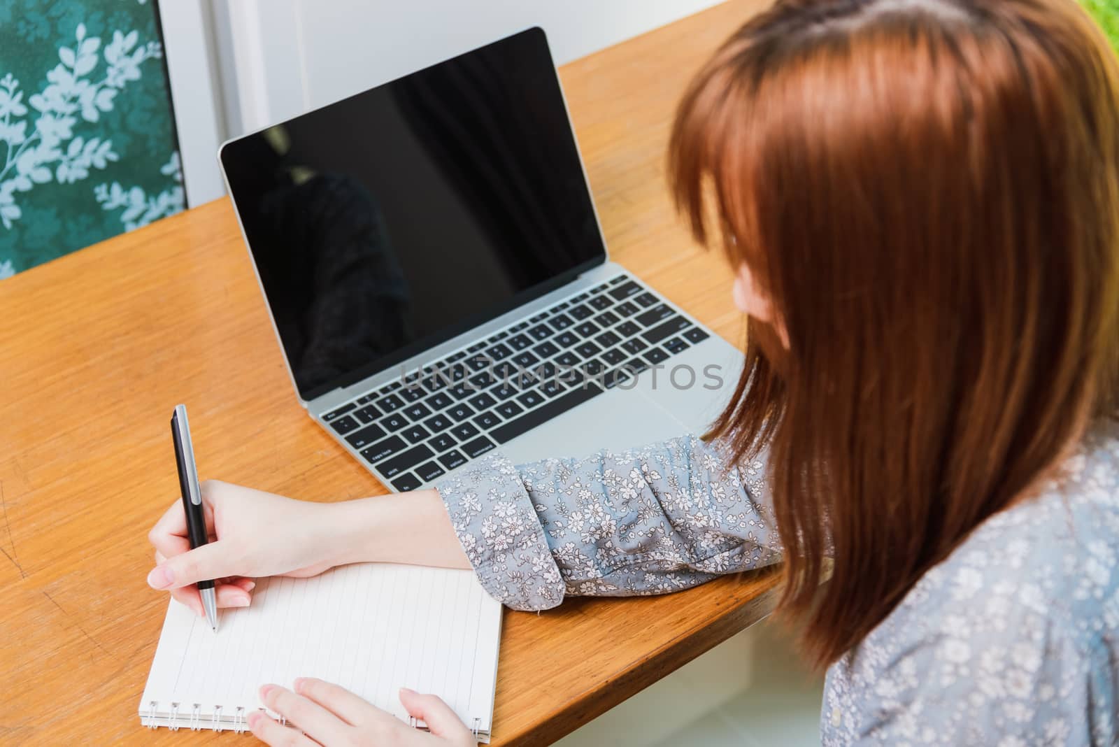 Asian young business woman wearing face mask protective working from home office with laptop computer he quarantines disease coronavirus or COVID-19 and write note booklist work today