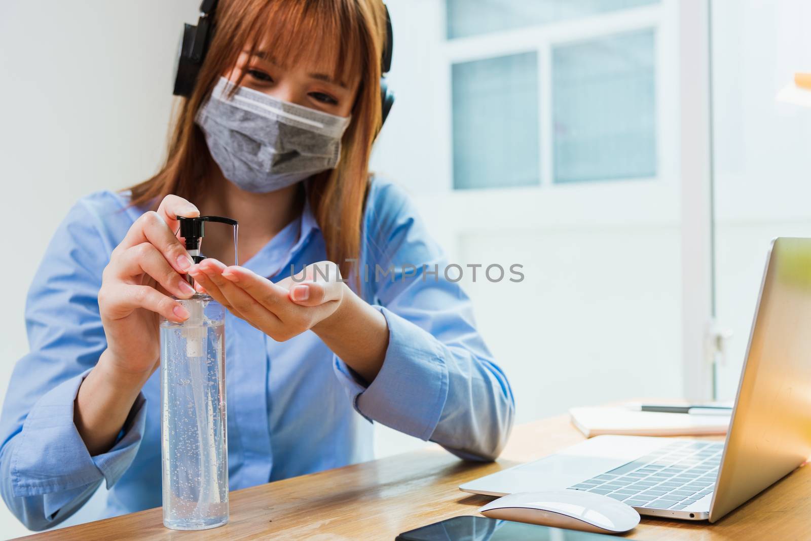 Asian young business woman wearing face mask protective working from home office with laptop computer he quarantines disease coronavirus or COVID-19 and cleaning hands with sanitizer alcohol gel pump