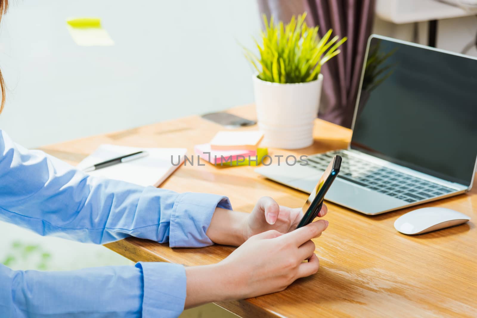 Asian young business woman wearing face mask protective using smart mobile phone for reading SMS message near laptop computer at home office quarantines disease coronavirus or COVID-19, work from home