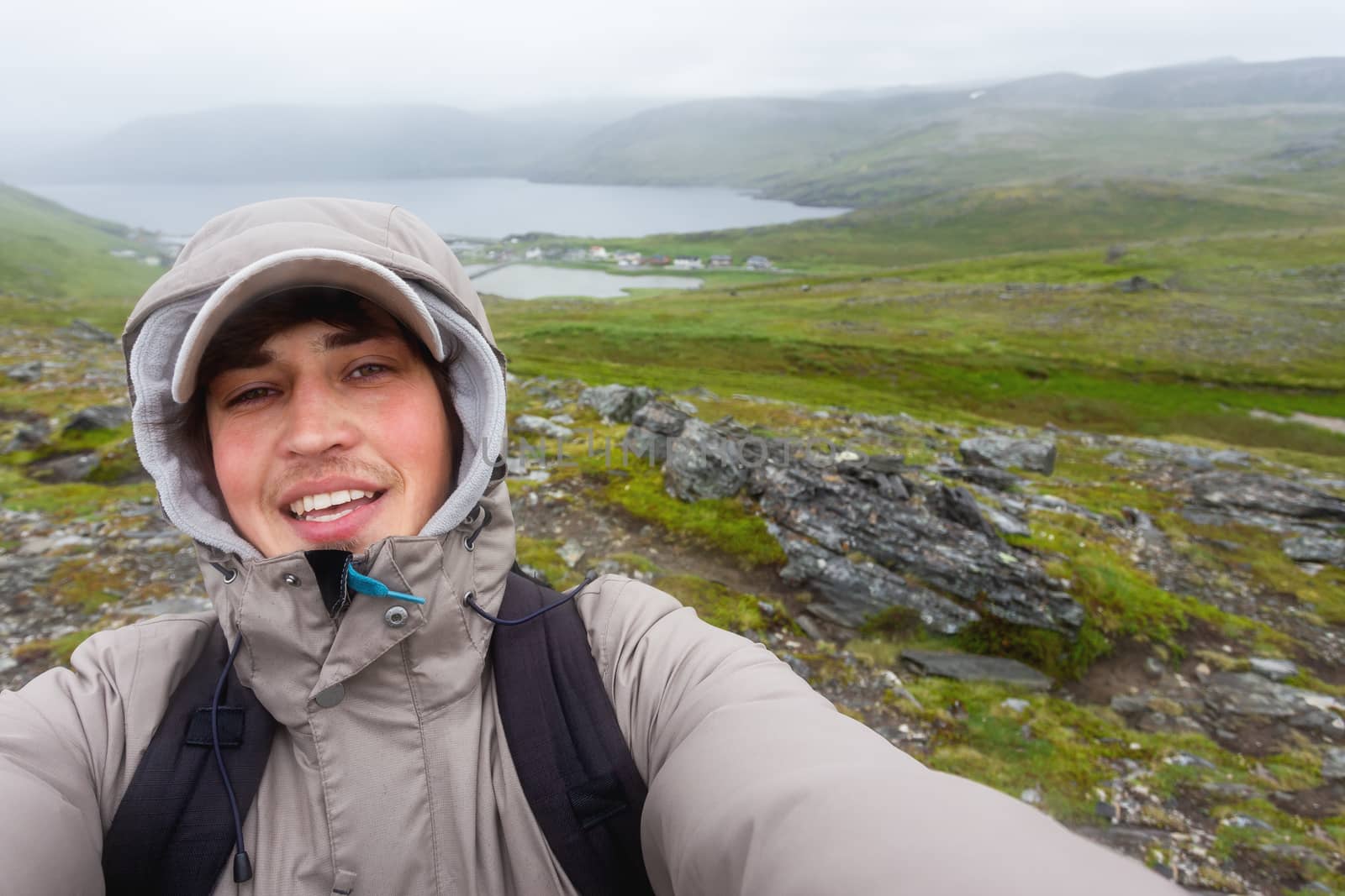 Tourist man making selfie on hill near Skarsvag (near Nordkapp). Landmark on Lofoten islands. Norway.