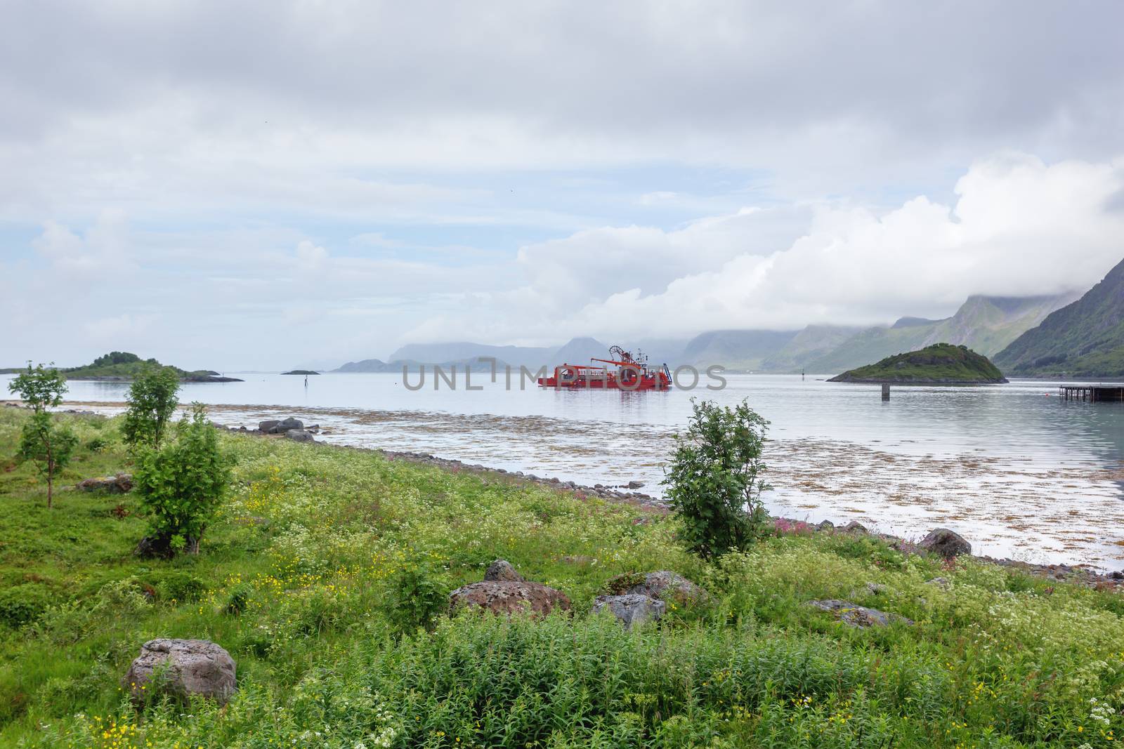 Special purpose ship in the waters of Lofoten archipelago. Typical scandinavian landscape with meadows, mountains and fjords. Lofoten islands, Norway.