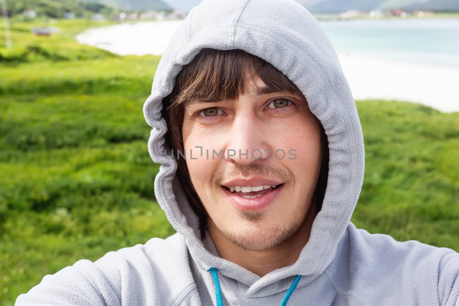 Tourist man making selfie on Rambergstranda beach on Lofoten islands. Beautiful sandy beach and azure water. Norway.