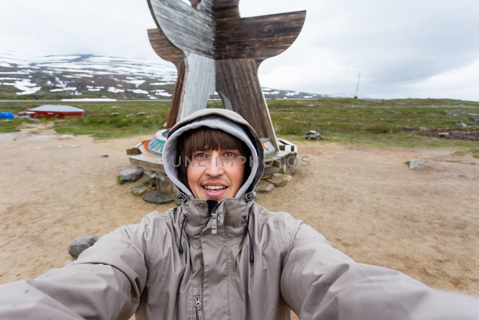 Tourist man making selfie Arctic circle center. Landmark on Lofoten islands. Norway.