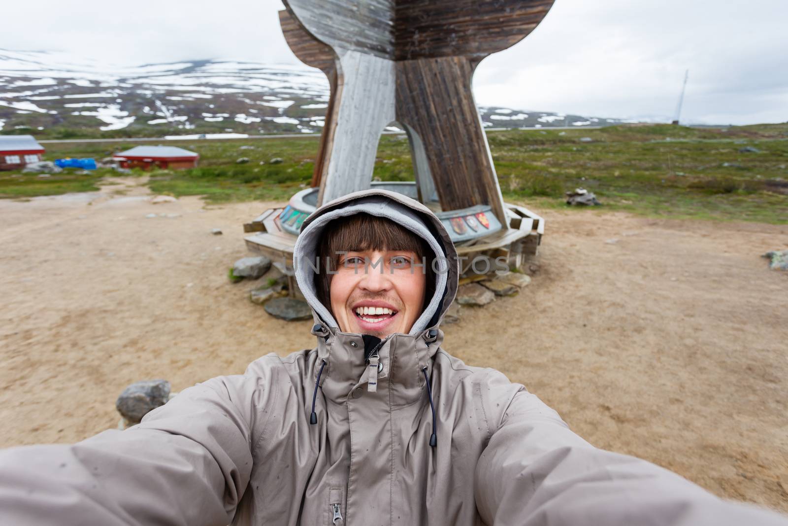 Tourist man making selfie Arctic circle center. Landmark on Lofoten islands. Norway.