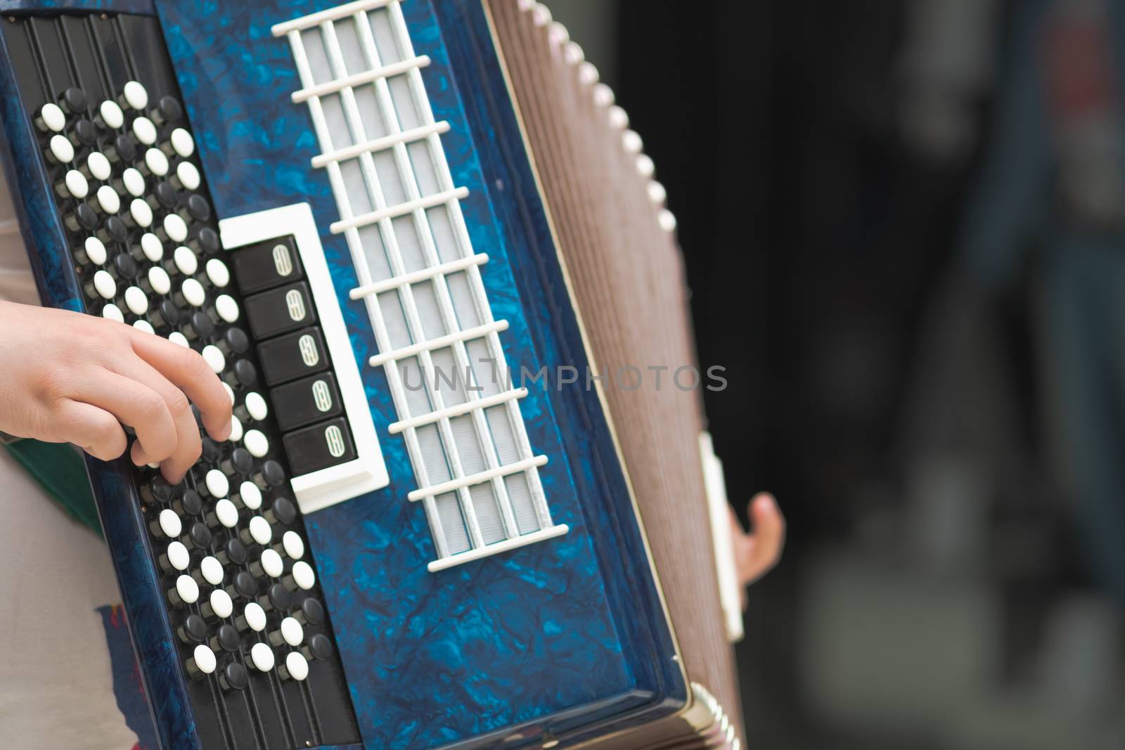 Accordion in the hands of a musician, close-up view. Street music image, busker playing a melodeon