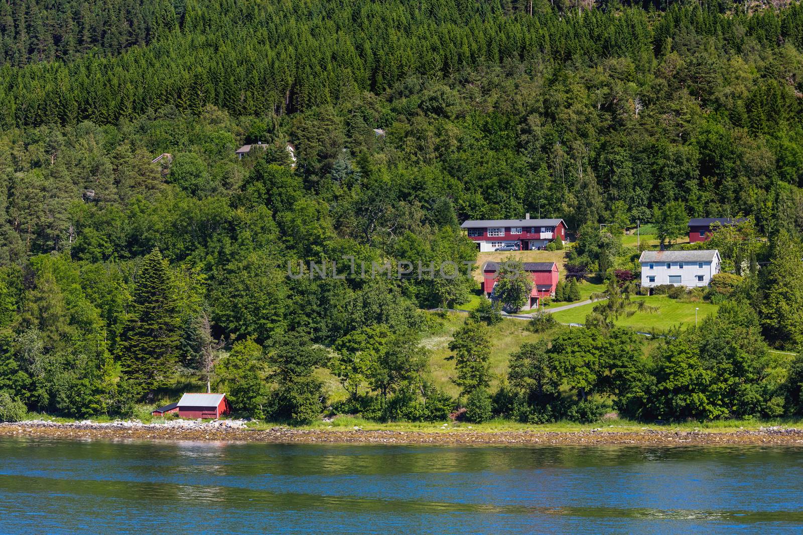 Typical scandinavian landscape with meadows and village. Houses with red walls and roofs. Norway.
