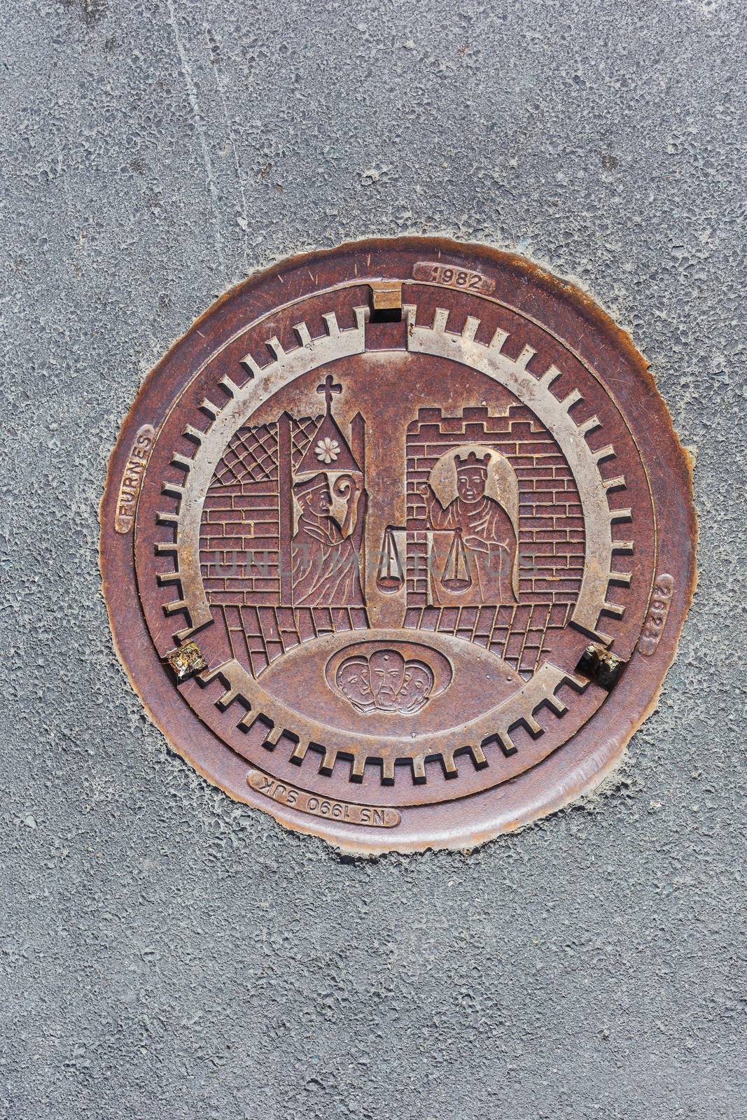 Metal sewerage hatchway with bas relief. Iron manhole with historic scene. Trondheim, Norway.