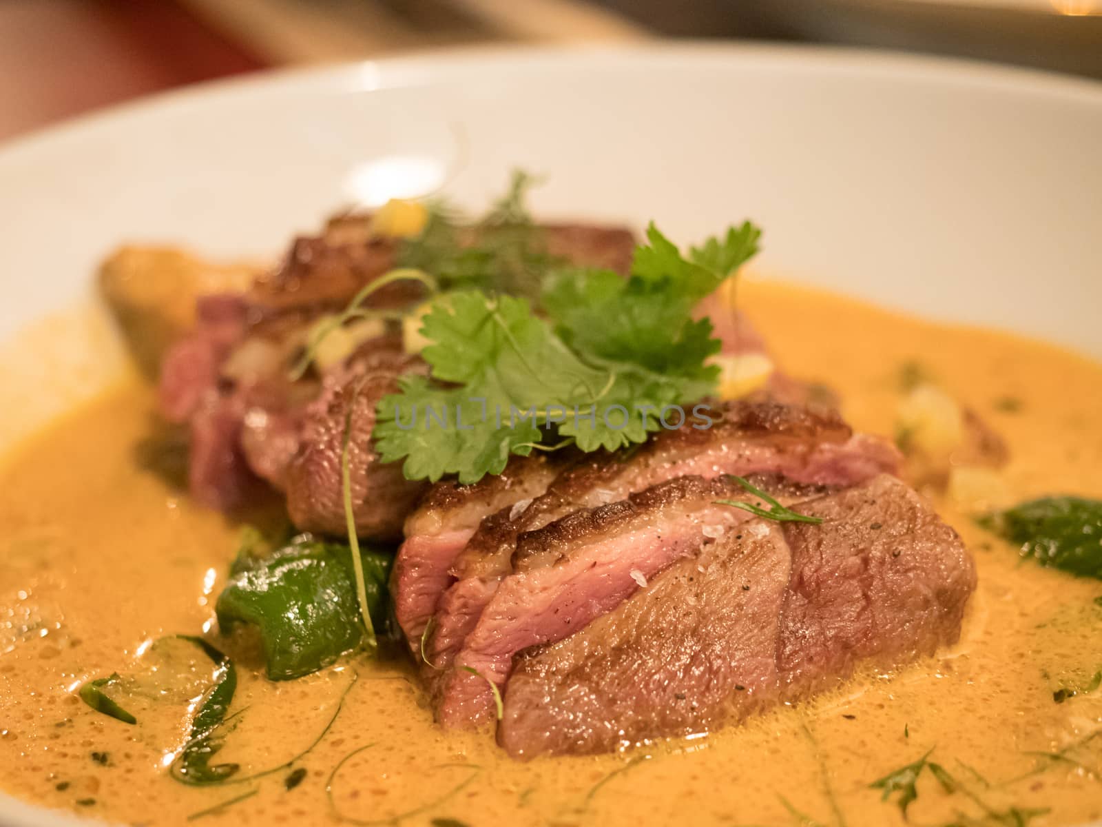 delicious piece of meat with orange sauce on white plate