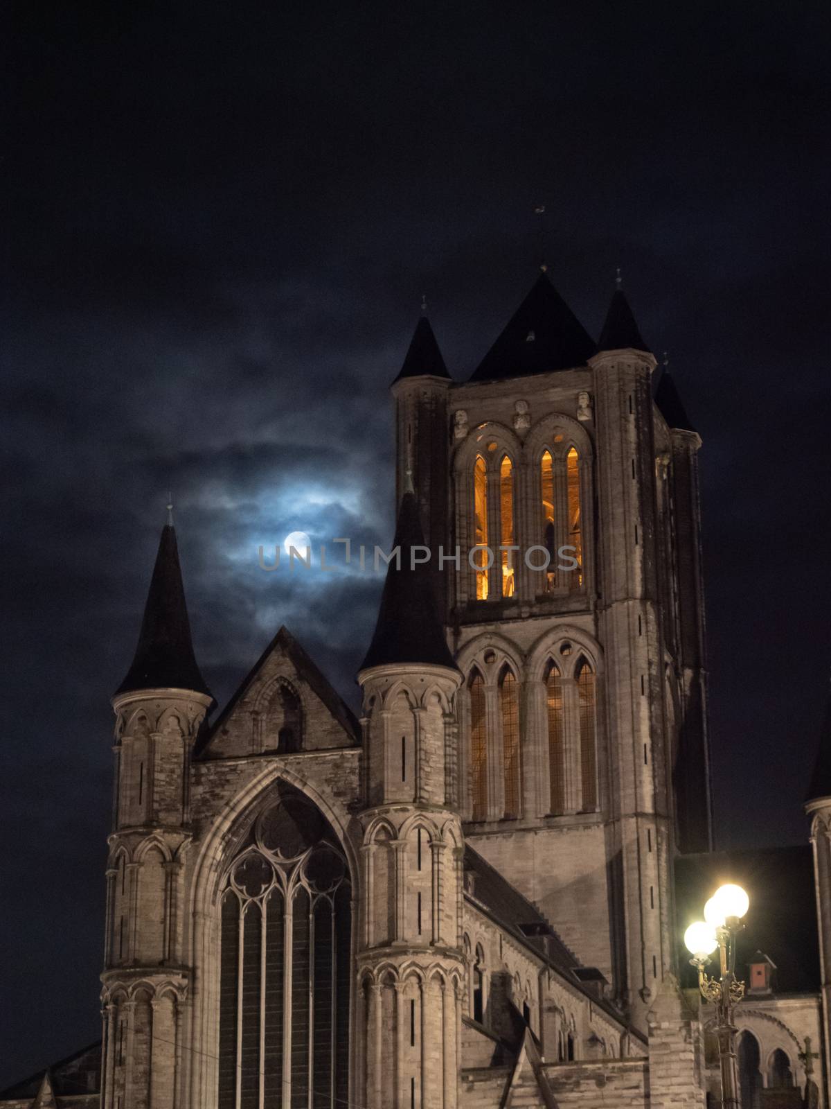 detail of the tower of Saint Nicholas Church, Ghent with the moon