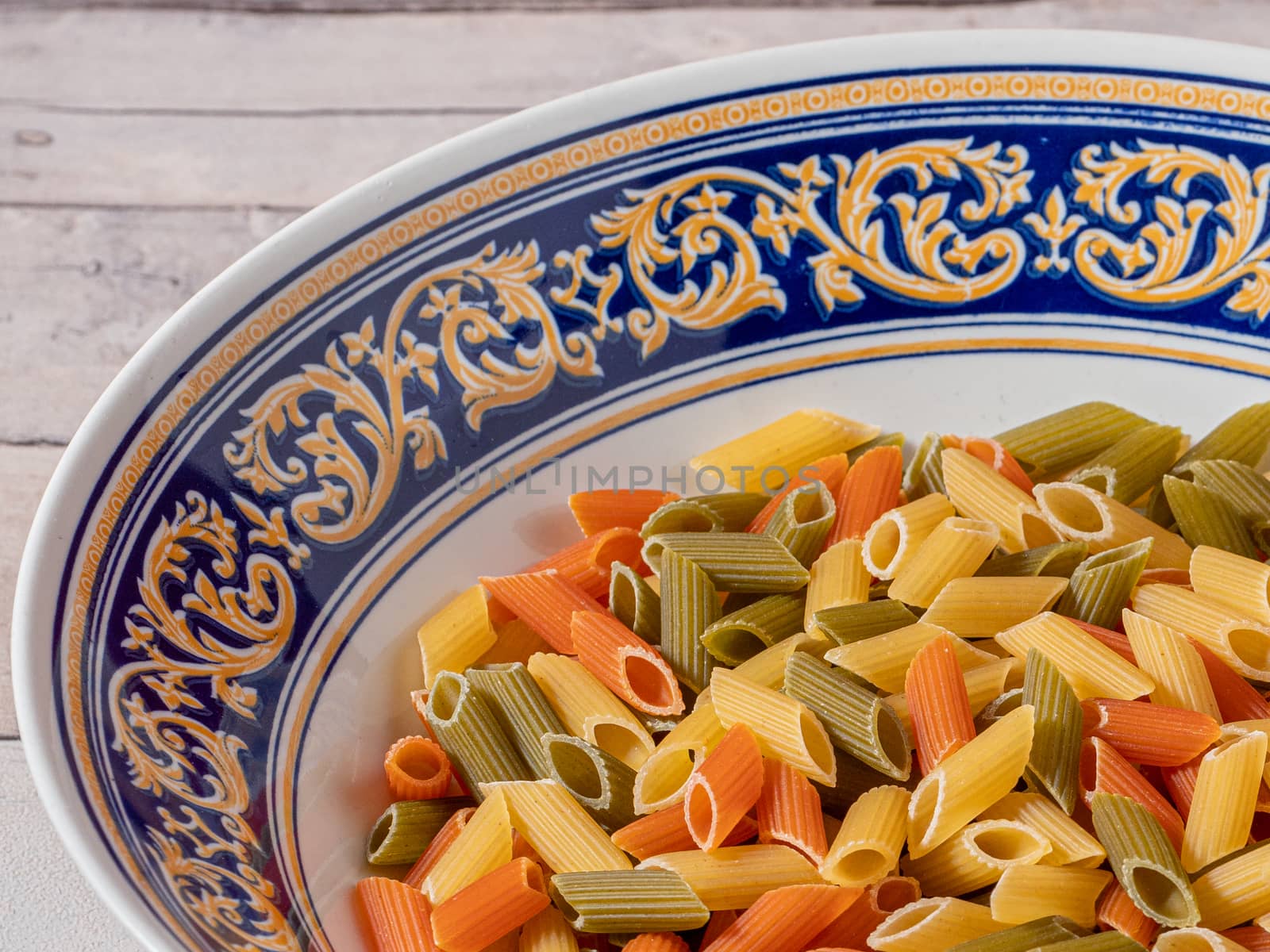 plate of raw macaroni on white wooden background