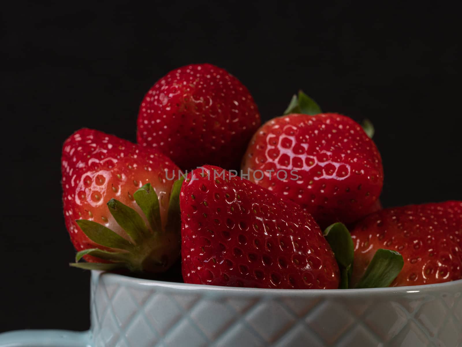 strawberries in a green ceramic cup