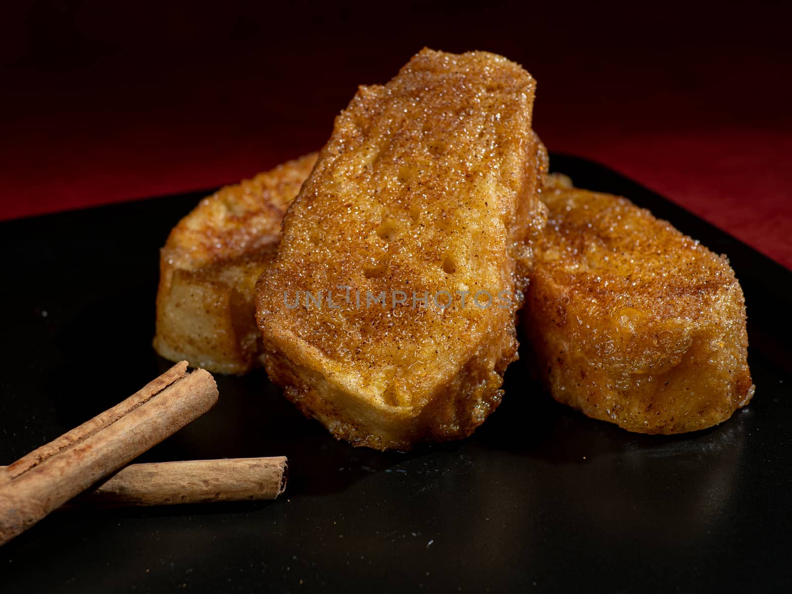 three french toast with cinnamon on black plate and dark background