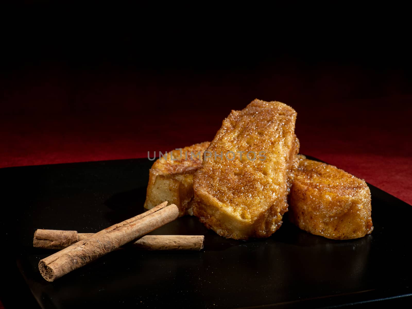 three french toast with cinnamon on black plate and dark background