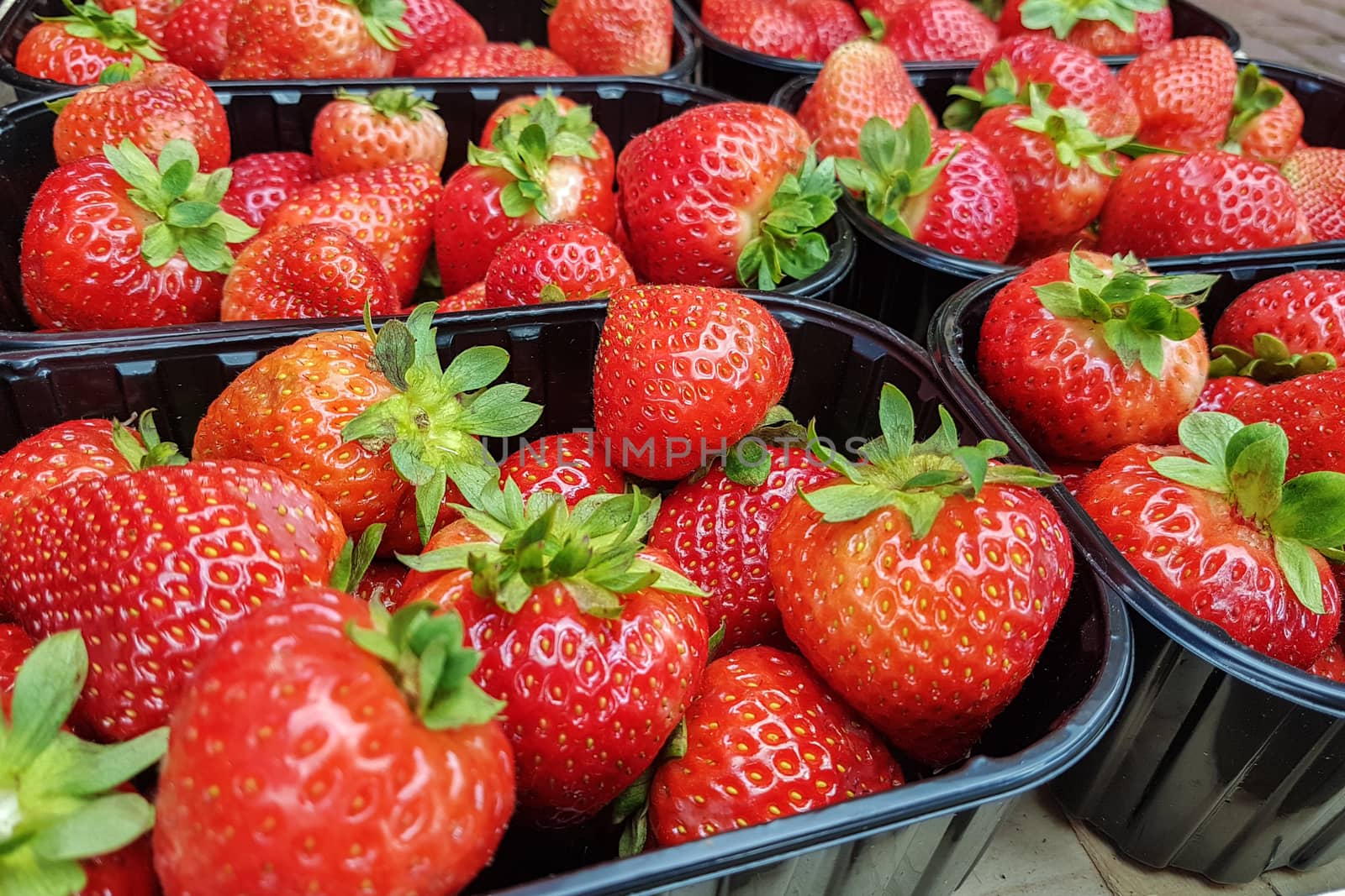 Fresh strawberries arranged in baskets ready for sale at marketplace.