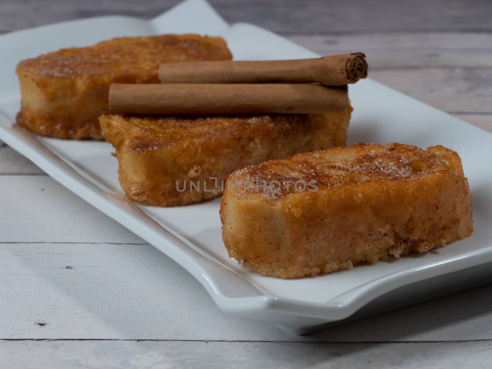 three french toast with cinnamon on white plate and light background