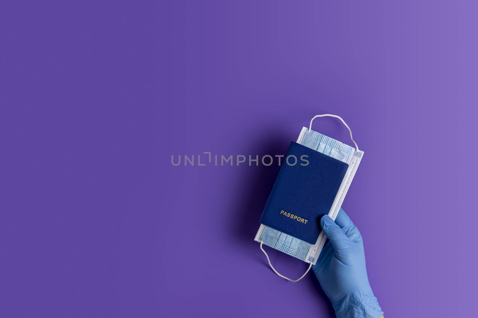 Doctor holds passports and respiratory surgical face mask in hands blue medical glove on violet background. Pandemic corona virus, insurance, airborne diseases, SARS, grippe