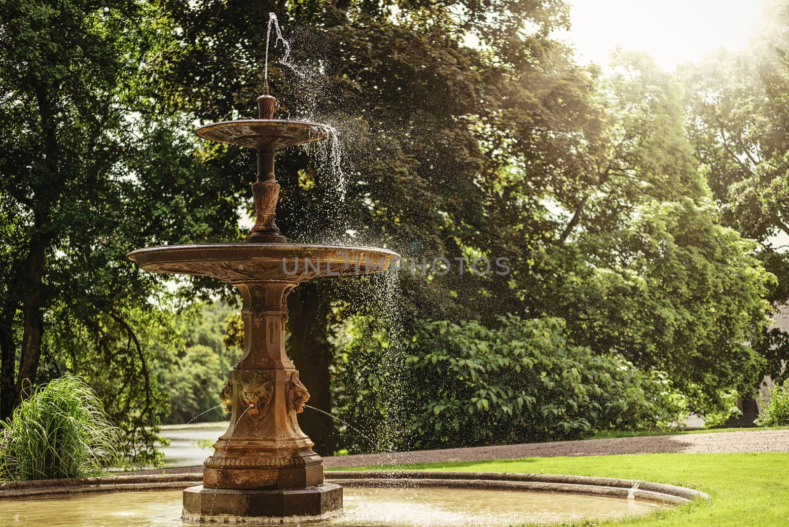 Archival and historical fountain in the park on a background of green trees on a sunny day (vintage effect)