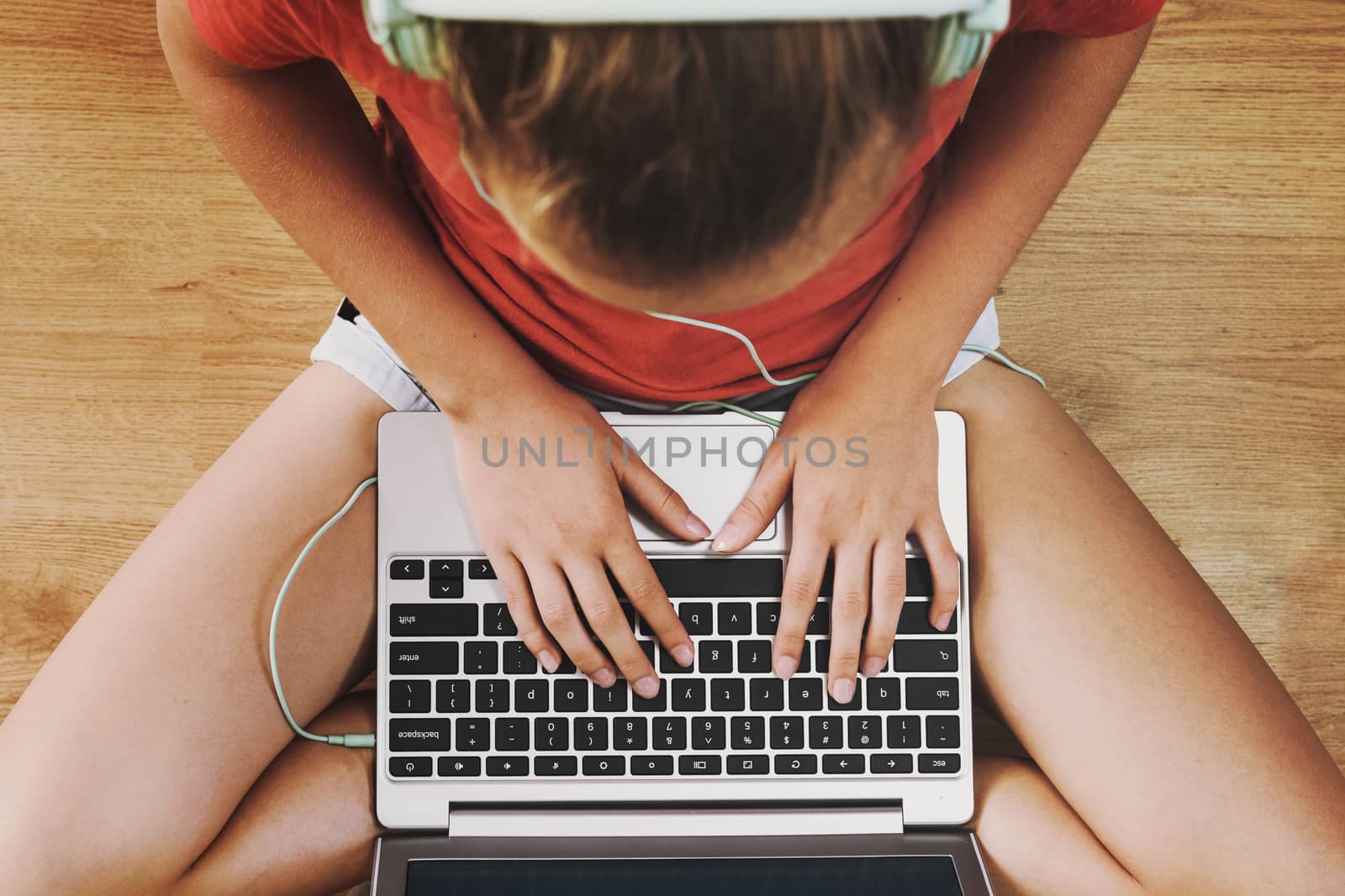 Top view of a girl sitting on the floor and communicating online on the internet on her laptop (vintage effect).