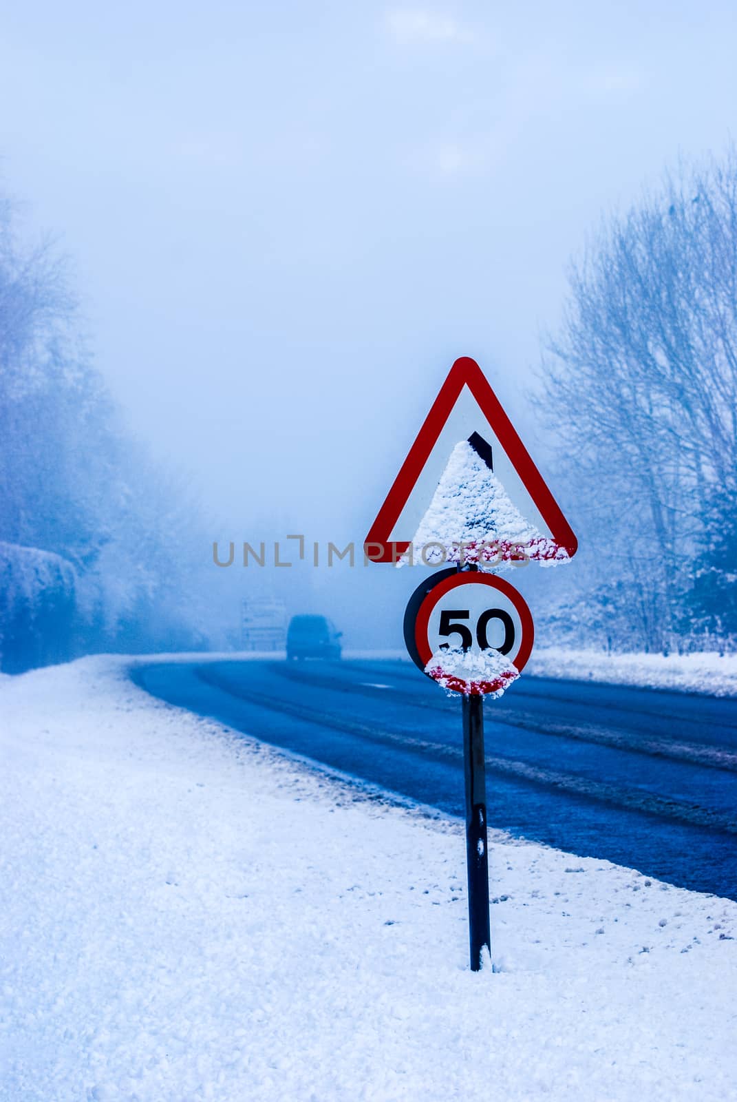 Snowy road with traffic sign and heavy snowfall on a country road.