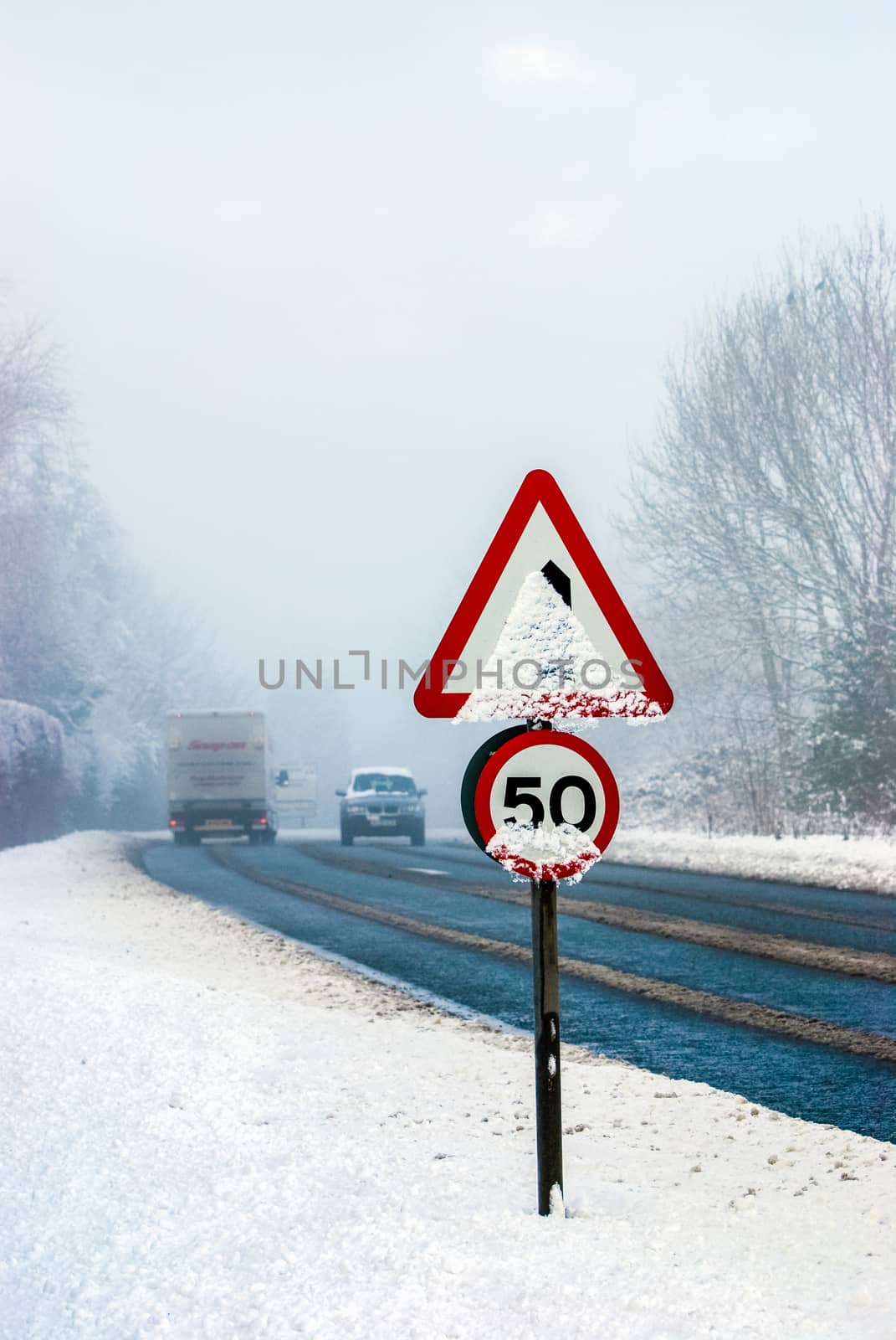 Snowy road with traffic sign and heavy snowfall on a country road. UK by paddythegolfer