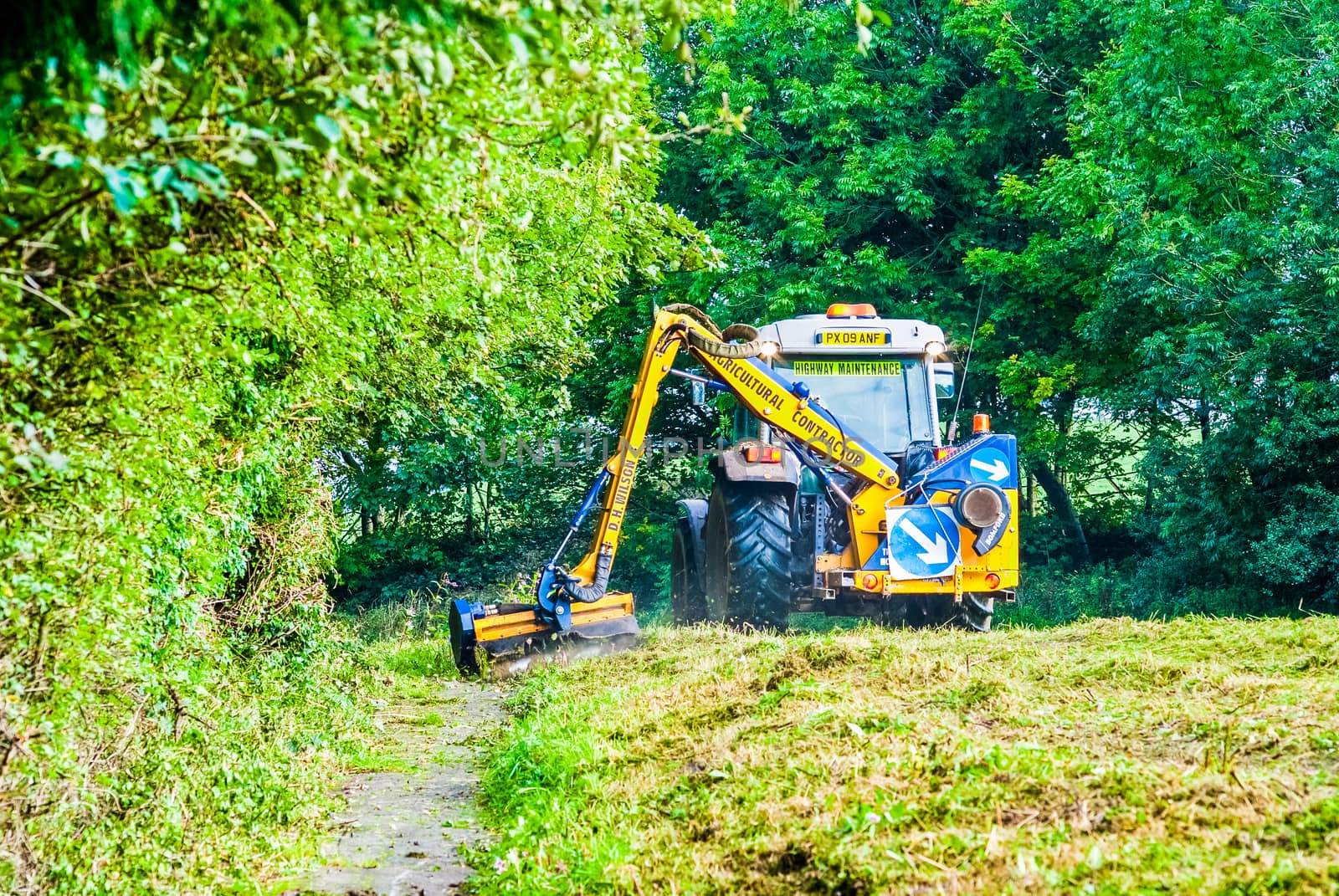 Tractor mowing grass along a road in UK by paddythegolfer